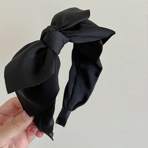 Detail of a large black fabric double-layer bow headband held to show soft texture