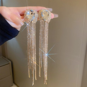 Dettaglio di orecchini lunghi con strass a goccia e nappine in argento scintillanti