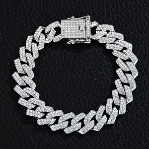 Macro shot of silver Cuban chain bracelet with pavé rhinestones on black leather background