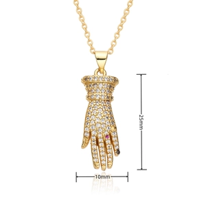 Macro shot of gold hand-shaped pendant with white and pink zircons, size 25x10mm
