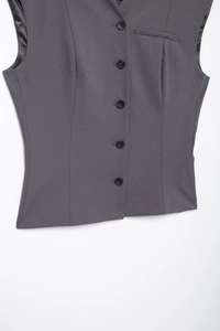 Detail of dark grey women vest showing five black buttons and front pocket texture