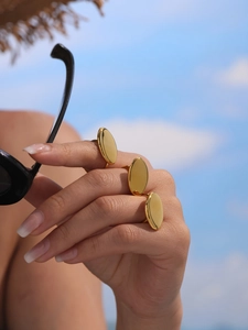 Close-up of three polished gold oval rings on hand with outdoor holiday backdrop
