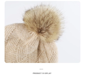 Detailed close-up of beige knitted beanie texture with fluffy brown faux fur pom-pom
