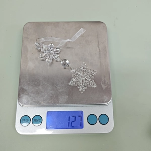 Weight measurement of clear acrylic Christmas snowflake ornament showing 12.7 grams