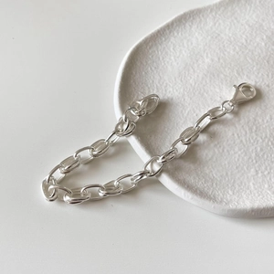 Detailed shot of silver 925 sterling chain bracelet with lobster clasp on ceramic plate