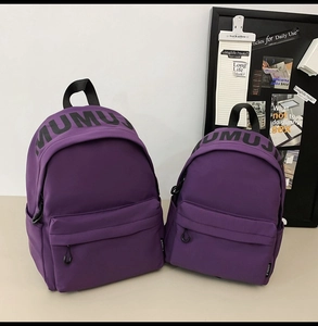 Detail view of purple nylon backpacks in two sizes with MUMUJ print and side pockets