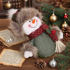 Christmas snowman doll with green body and fur hat on a rustic wooden holiday tabletop