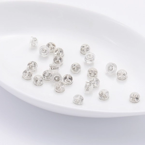 Silicone earring backs with metal core inserts shown scattered on white tray