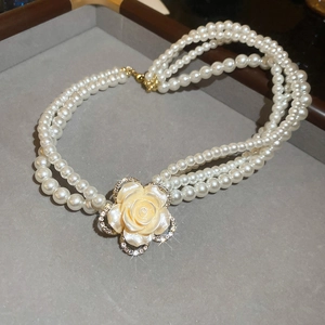 Detail of multi-layer pearl necklace featuring a diamond-encrusted rose pendant in vintage style