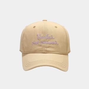 Close-up of beige cotton baseball cap with purple Vouloir c'est pouvoir embroidery
