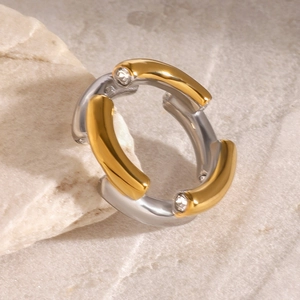 Bicolor-Ring aus 18k Gold und Edelstahl mit Kristallakzenten auf Naturstein-Hintergrund