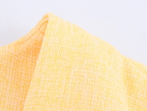 Dettaglio ravvicinato della trama in tessuto tweed giallo della giacca corta elegante