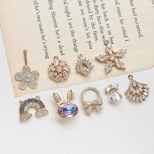 Close-up of golden copper charms with zircon snowflakes and rainbow motifs for DIY jewelry