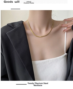 Detailed view of a trendy golden titanium steel chain necklace worn by a fashion model