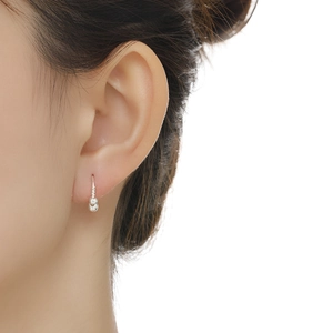 Close-up detail of silver bead earrings on model ear showing petite minimalist design