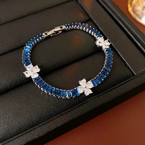 Detail of luxury clover bracelet with blue rectangle gems and white zircon flowers