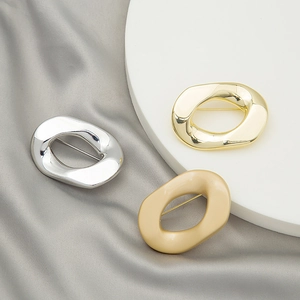 Irregular geometric metal brooches in silver, gold, and matte gold on silk fabric
