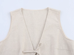 Dettaglio gilet beige in lino con scollo a V, chiusura a laccetti e trama intrecciata