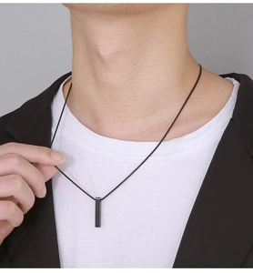 Close-up of minimalist black rectangle pillar pendant necklace on a male model