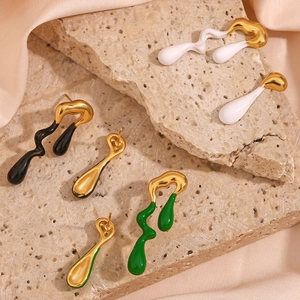 Detailed view of irregular liquid lava earrings in gold and enamel on a textured stone