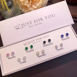 Close-up of 7 pairs of colorful butterfly stud earrings in a white weekly gift box