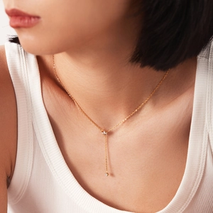 Detail of gold Y-shaped necklace with crown charm and round cubic zirconia pendant