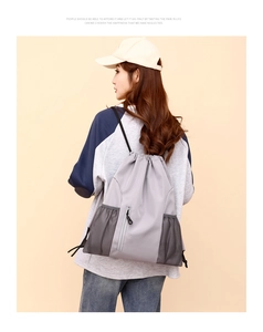 Detailansicht des lässigen grauen Oxford-Stoff-Kordelzugrucksacks mit Netztaschen.