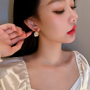 Close-up of red and gold square earrings with crystals on an elegant female model