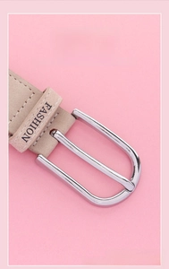 Detail of silver alloy buckle with fashion text on a beige elastic canvas belt