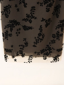 Détail de tissu en maille beige avec motif floral noir et coutures de l'ourlet