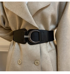 Detail of a wide elastic black waist belt with a silver C-shaped textured metal buckle