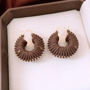 Gros plan de boucles d'oreilles créoles tressées en cuir dans un écrin marron