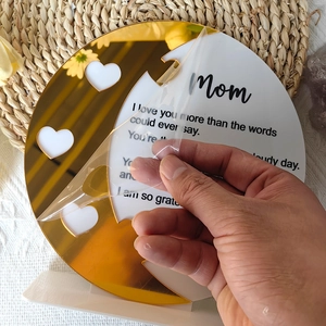 Detail of hand peeling protective film from acrylic Mom heart plaque gift decoration