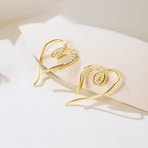 Detailed macro view of heart shaped gold plated earrings with white zircon inlay craft