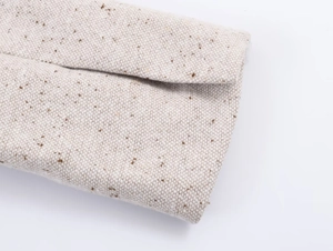 Détail macro de la texture du tissu en tweed écru avec des mouchetures brunes sur la veste