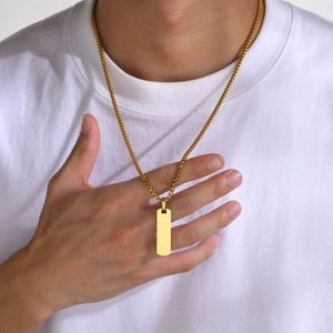 Polished gold rectangular pendant necklace worn by model on a white shirt