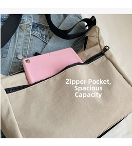 Detailed view of spacious canvas crossbody bag showing large zipper pocket with tablet storage