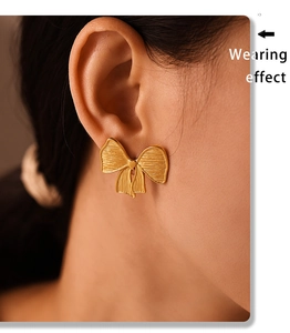 Wearing effect of golden bow stud earrings in polished PVD plated stainless steel