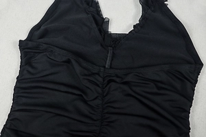 Detail of elegant black dress showing ruching fabric texture and mesh lace trim