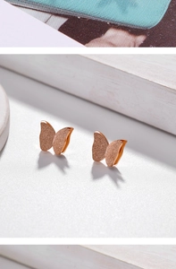 Detailed macro view of 18k rose gold butterfly studs with a frosted glitter texture