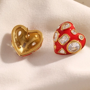 Macro detail of red heart earrings with gold trim and crystal inlay on silk