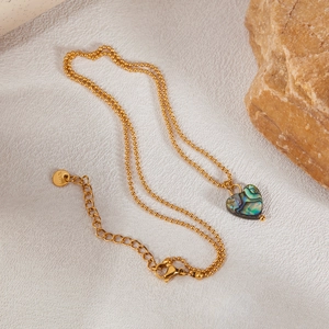 Golden heart necklace with iridescent abalone shell inlay on white textured fabric