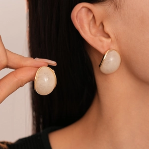 Retro resin oval stud earrings in white and gold finish shown on a model's ear