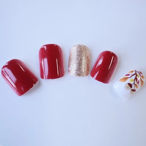 Short square press-on nails with burgundy finish, gold glitter, and autumn leaf designs