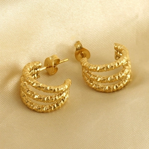 Three-layer gold C-shaped earrings with hammered texture on elegant gold satin fabric