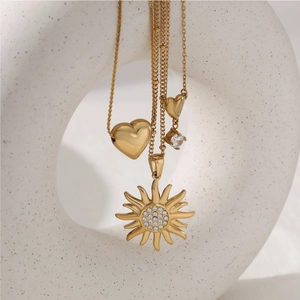 Collier en acier inoxydable doré avec pendentifs soleil et cœur sur support en céramique