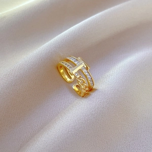 Macro shot of gold adjustable ring featuring Cuban chain and T-shaped pavé diamond details