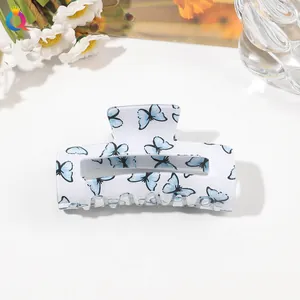 Macro shot of large white acrylic hair claw clip with delicate blue butterfly patterns