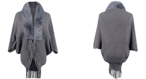 Detailed view of grey knitted poncho featuring a plush faux fur collar and tassel hem