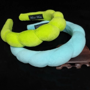 Handmade twisted plush headband in neon green and light blue colors on black background
